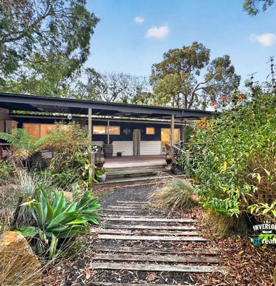 This inviting home features a spacious front porch and lush gardens, perfect for outdoor relaxation.