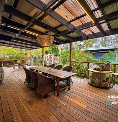 Spacious outdoor entertaining area featuring a large dining table, surrounded by lush greenery and a cozy atmosphere.