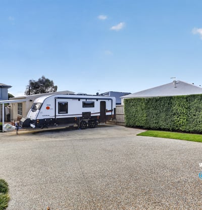 Spacious driveway perfectly accommodates an RV, surrounded by well-maintained landscaping for added privacy and convenience.