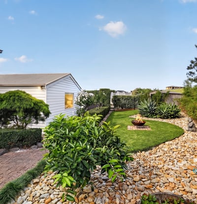 Discover a tranquil outdoor space featuring neat landscaping, unique planting beds, and a cozy fire pit area.