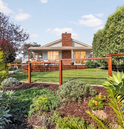 Discover a beautifully landscaped property featuring a spacious backyard with vibrant greenery and ample outdoor space.
