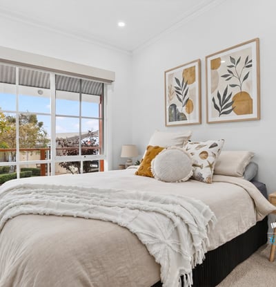 Bright and inviting bedroom featuring large windows, modern decor, and a cozy atmosphere for relaxation.