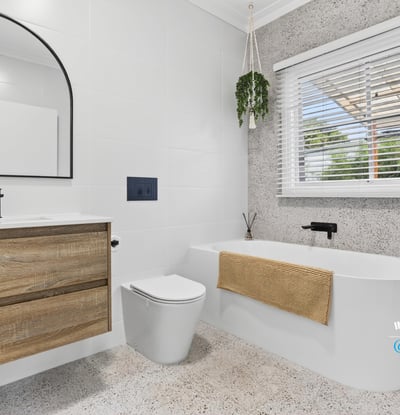 Modern bathroom featuring a freestanding tub, large mirror, and ample natural light from the window.