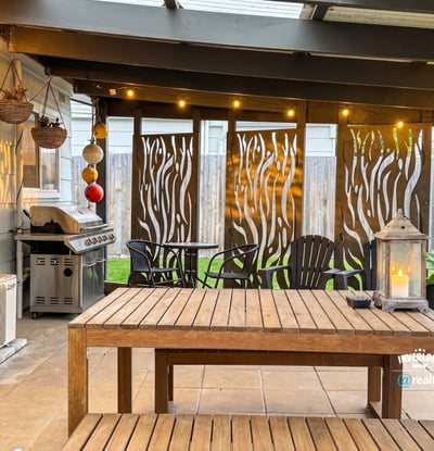 Discover an inviting outdoor space featuring a cozy dining area, grill, and decorative privacy screens.