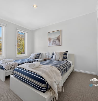 Bright and inviting bedroom with ample natural light, featuring twin beds and modern aesthetics.