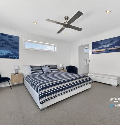 Light-filled bedroom featuring modern decor, ample space, and beautiful ocean-themed artwork for a refreshing atmosphere.