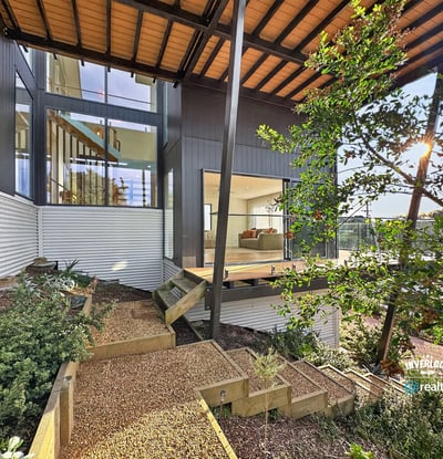 Contemporary home featuring expansive windows, a spacious deck, and beautifully landscaped outdoor areas for relaxation.