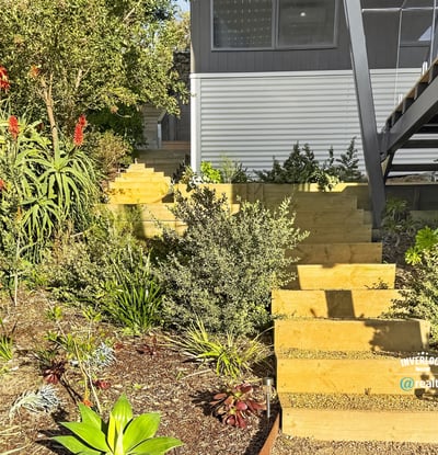 This unique home features a beautifully landscaped garden with inviting wooden steps leading to an open entry.