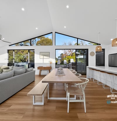 Bright and open living space seamlessly connects dining and kitchen areas, featuring large windows with natural light.