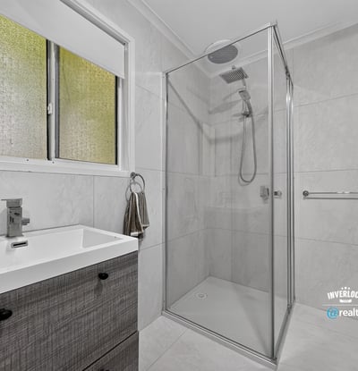 Modern bathroom featuring a walk-in shower and sleek cabinetry, designed for functionality and comfort.