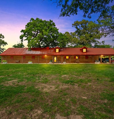 Discover this spacious home set on a sprawling green lot, featuring a distinctive red roof and open outdoor space.