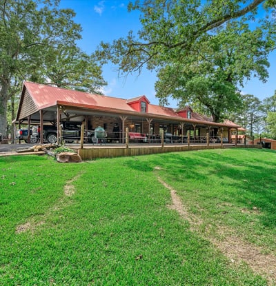Spacious property featuring a large covered porch, surrounded by lush greenery and scenic views.