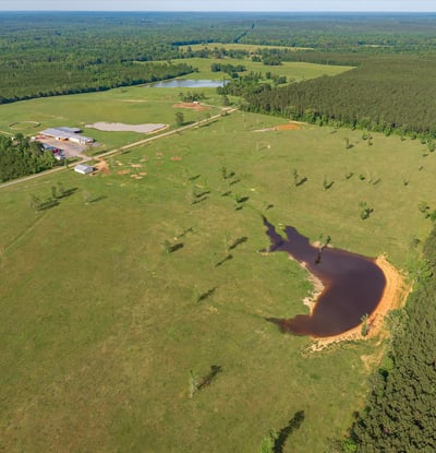 Spacious, picturesque land featuring open fields, a tranquil pond, and surrounding wooded areas, ideal for development.