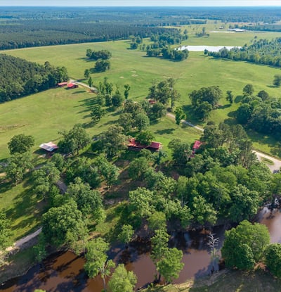 Expansive acreage with lush landscapes, multiple structures, and serene water features ideal for various outdoor endeavors.