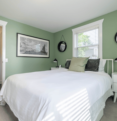 Bright bedroom featuring a cozy layout with fresh green walls and ample natural light.