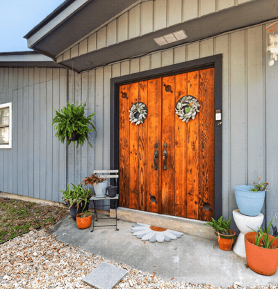 Inviting rear entryway featuring distinctive double doors and vibrant planters, perfect for welcoming guests home.
