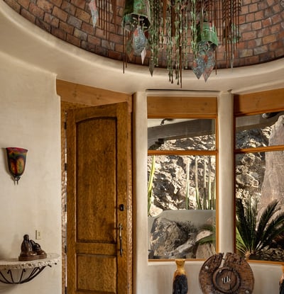 Greet guests with artisan craftsmanship at every turn starting with this custom-carved front door and original Soleri bell chandelier. A captivating welcome that sets the tone for the home s unique design throughout.