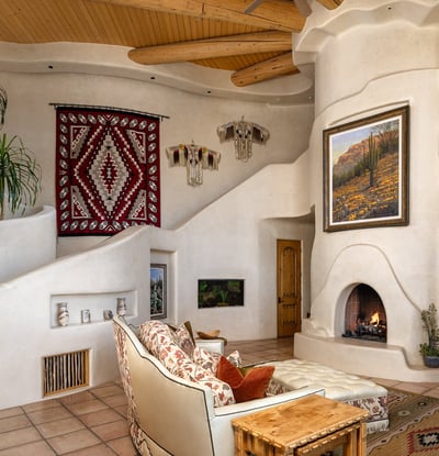 Unique architectural curves, built-in niches, and earthy textures make this family room cozy yet elevated. A central fireplace adds ambiance, while the open layout ensures comfort for guests or quiet nights in.