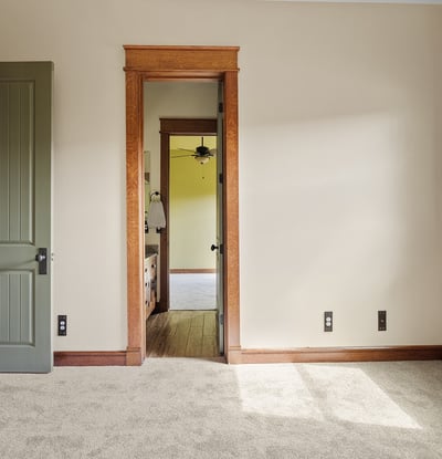 Bright bedroom with soft carpeting, wood-trimmed windows, and classic design elements. A comfortable space filled with natural light and timeless appeal.