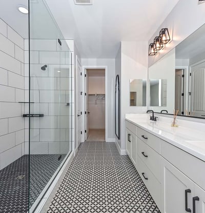 A luxurious retreat featuring geometric tile floors, walk-in glass shower, dual sinks, and upgraded matte black fixtures.
