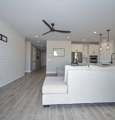 This spacious great room boasts wood-look tile flooring, recessed lighting, and a shiplap accent wall blending warmth with a modern aesthetic in this Peoria home.