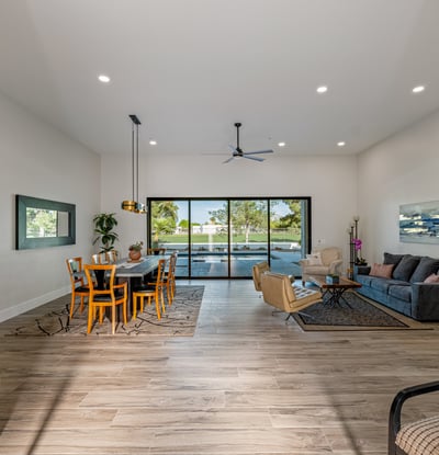 The great room blends dining and living areas with high ceilings, wood-look flooring, and seamless backyard access.