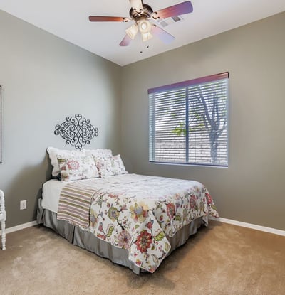Light-filled guest bedroom with neutral paint, ceiling fan, and closet space, perfect for visitors or daily use.