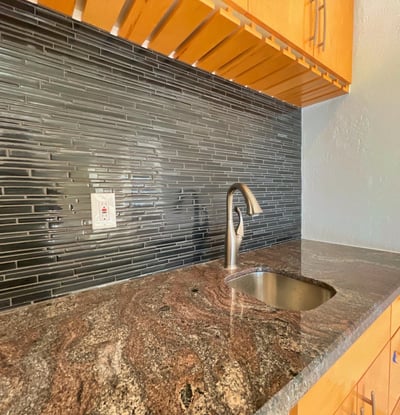 Contemporary wet bar accented with granite surfaces and glass-tile details. Perfectly suited for stylish entertaining and everyday convenience.