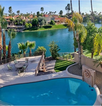 Resort-style setting featuring sparkling pool, lush palms, and lakefront patio. Scottsdale outdoor living at its finest.