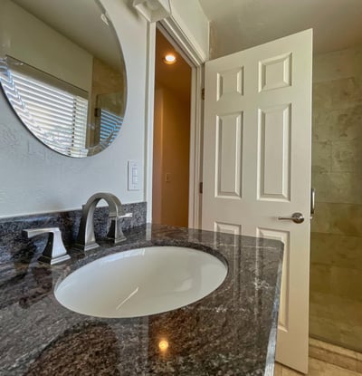 Bright modern bathroom boasting granite countertops, polished fixtures, and tiled shower enclosure for a sleek, refined look.