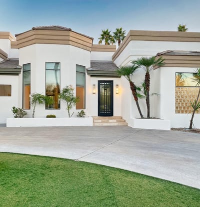 Striking entryway with tall windows, modern iron door, and smooth stucco finish for a sophisticated curb presence.