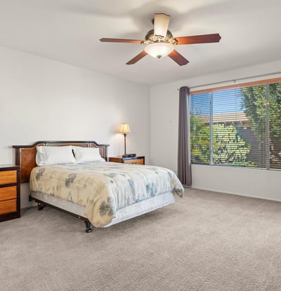 Spacious primary bedroom with neutral d cor and scenic backyard views. Soft carpeting and ceiling fan comfort make this an ideal retreat.