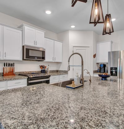 Crisp white cabinets, granite countertops, and a gas range bring style and function together. Natural and recessed lighting create a bright, inviting Litchfield Park kitchen.