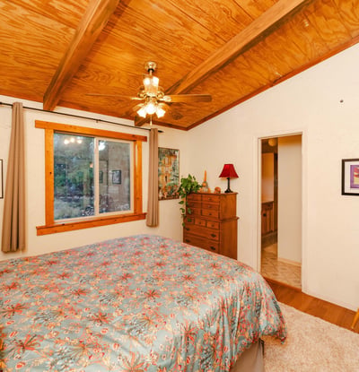 This restful primary bedroom showcases warm wood ceilings, soft textures, and scenic outdoor views. Its rustic charm reflects the essence of quiet living in Hackberry s desert landscape.