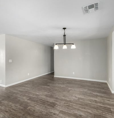 Clean and bright dining space with updated pendant lighting, neutral paint, and durable wood-look tile flooring an ideal setting for entertaining in this Phoenix home for sale.