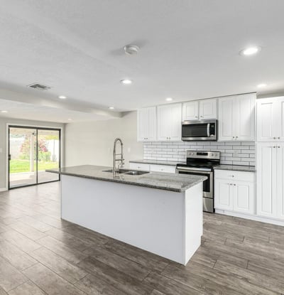 Beautiful kitchen featuring granite countertops, a large island with seating, stainless steel appliances, subway tile backsplash, and white cabinetry perfect for cooking and hosting in Phoenix.