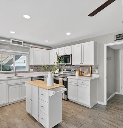 Updated kitchen showcasing white cabinetry, contemporary backsplash, stainless appliances, and abundant counter space.