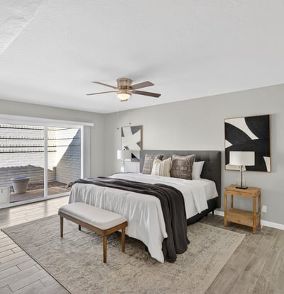 Relaxing primary suite featuring ceiling fan, soft natural light, and direct access to a private courtyard for peaceful mornings.