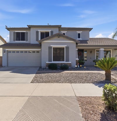 Attractive exterior of this Queen Creek property featuring a covered entry, desert landscaping, and attached garage in the popular Cortina community.
