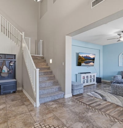 Welcoming entry foyer with soaring ceilings, tile flooring, and staircase leading to the loft and upper living areas of this spacious Queen Creek home.