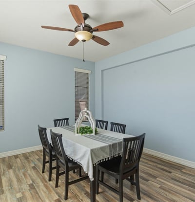 Bright dining room with wood-style flooring, ceiling fan, and neutral walls creating a welcoming setting for gatherings and meals.