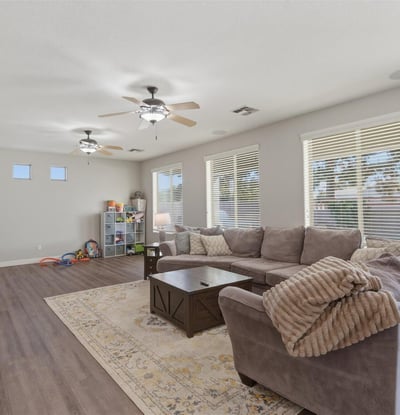 Large family room with multiple windows and modern flooring, offering plenty of space for relaxing, entertaining, or movie nights.