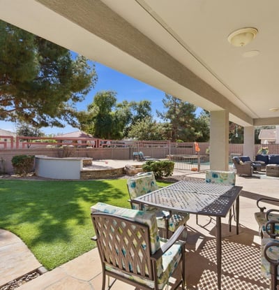 Shaded patio overlooking the landscaped yard and pool area, providing a comfortable outdoor living space for dining or relaxing.