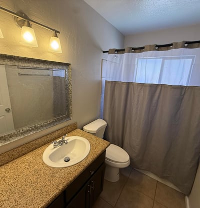 Secondary bathroom featuring granite vanity counter, modern lighting, and full shower area. Functional layout provides convenience for guests and everyday living.
