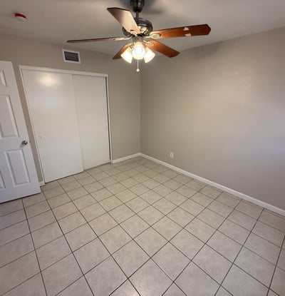 Bright bedroom with tile flooring and ceiling fan light fixture. The simple layout provides flexibility for furniture arrangement and everyday comfort.
