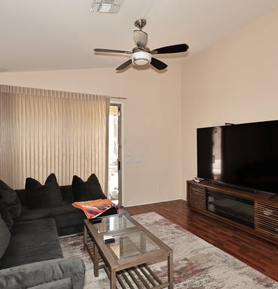 Spacious living area with ceiling fan, wood-look floors, and patio access. Perfect for everyday living and entertaining in this Phoenix property.