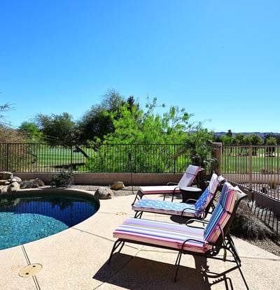 Inviting backyard lounge area next to a Pebble Tec pool with golf course views. This Phoenix property creates a relaxing outdoor retreat with scenic surroundings.