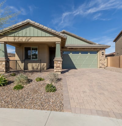 Stunning Peoria home exterior with paver driveway, stone detailing, and desert landscaping. Offers low-maintenance living and strong curb appeal.