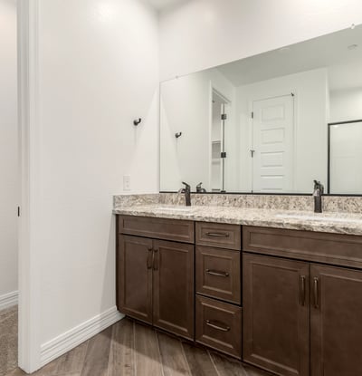 Primary bathroom with dual vanities, granite surfaces, and ample storage. A blend of style and everyday functionality.