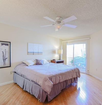 Primary bedroom with natural light, ceiling fan, and sliding door access to the backyard, offering a relaxing private retreat.